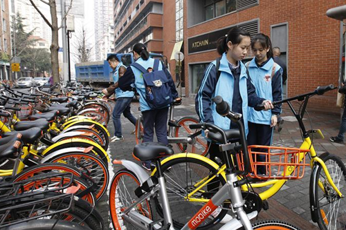 013月25日，学生志愿者在路边整理不规范停放的共享自行车。
